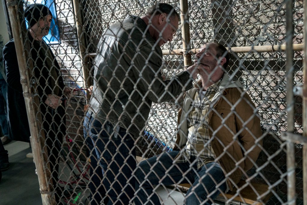 Alvin (Elias Koteas) regarde Hank malmener un suspect dans la cage